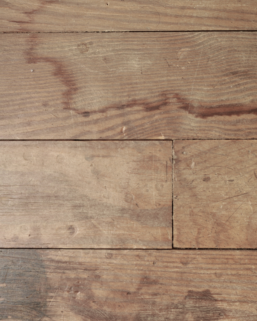 経年劣化や使用状態によってダメージを受けた床。水染みや傷がついたフローリングの参考画像。