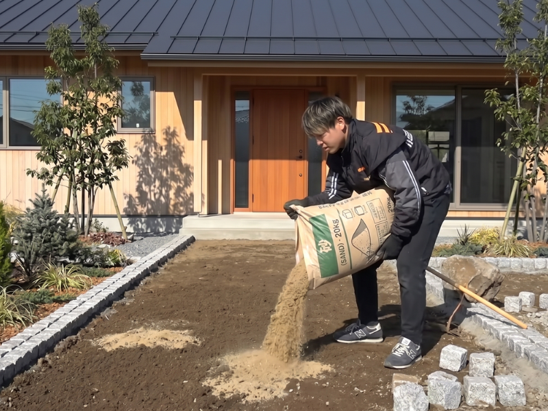 庭にタイルを置くだけDIYのため砂を入れて地面を平滑にする作業